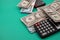 Top closeup of a pack of dollars black calculators around on the green background