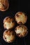 Top closeup view of a group of mini chocolate chip muffins on black slate.