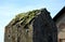 The top of the concrete pillar in the shape of a roof overgrown with hills of green moss. stele in the shape of an obelisk, tombst