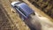 Top down aerial view of fast driving car on dirt road leaving cloud of dust behind.