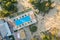 Top down aerial view of hotel swimming pool with crystal blue water surrounded with palm trees and deck laying chairs in resort