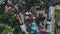 A top-down aerial view of the roofs of houses of a small town with a river, trees and cars.