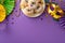 Top-down shot of plate adorned with scrumptious cupcakes, opulent masquerade mask, classic necklaces on purple backdrop