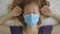 Top-down shot of a young woman in a medical mask that stays in mandatory quarantine. She was in one room for two weeks