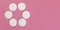Top down view, 6 face cleaning cotton pads arranged in circle, on pink board, wide banner space for text right