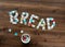 Top down view of bread tags used to form the word bread on a dark wooden table.