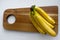 Top down view of a bunch of yellow bananas which are laying on a wooden cutting board