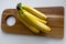 Top down view of a bunch of yellow bananas which are laying on a wooden cutting board