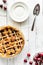 Top down view of a freshly baked lattice cherry pie with plates for serving.