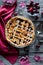 Top down view of a freshly baked lattice cherry pie on a rustic wooden table.