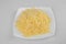 Top down view of grated cheese in white plate on white background. Topping.