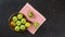 Top down view, green apples and pears in wooden carved bowl, red chequered tablecloth and black marble board under