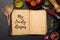 Top-down view of a kitchen table with ingredients, utensils, and an open cookbook