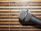 Top-Down View of A Microphone Head and Silver Grille on A Striped Yellow and Black Bamboo Mat Background. Karaoke Bar, Party