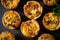 Top-down view of a mini quiche with a flaky crust, runny egg filling, and crisp bacon bits, served in a cute muffin tin