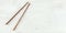 Top down view - pair of dark wood chopsticks on white board. Can be used as banner for asian / chinese food, space for text on