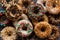 Top down view of a pile of assorted homemade donuts with different toppings.