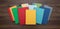 Top down view of a pile of bright colorful books centered on a dark desk