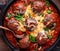 Top down view of a skillet filled with saucy meatballs covered in melted cheese and garnished with basil.