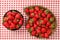 Top down view, strawberries in black and wooden carved bowl on red gingham pattern tablecloth