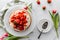 Top down view of a strawberry shortcake on a cake platter with serving dishes to the side.