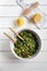 Top down view of a tabbouleh salad on white wooden background with lemon on cutting board