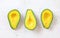 Top down view, three avocado halves on white working board