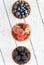 A top down view of three waffle bowls filled with blueberries, strawberries and blackberries on a wooden table.