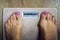 Top-down view to female bare feet standing on scale with written word overweight on display. Concept fitness and loosing weight.