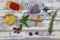 Top down view on white timber plank table with gin tonic glass, red pepper, lavender, rosemary, sage, cranberries, anise