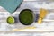 Top down view on white wood table with chawan bowl, bamboo whisk and spoon, can green matcha tea powder and blue napkin