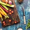 Top down view of a wooden cutting board topped with raw vegetables used in cooking mirepoix. Instagram crop.