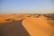 At the top of the dune with endless views in bright colors from the sunset, in the Omani desert, Wahiba Sands / Sharqiya Sands, Om