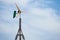 Top end of self build wind turbine made out of wood while generating energy in front of an overcast sky. The blades are blurred fr