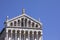 Top of facade of Pisa Cathedral with arcades and statue. Architectural details close up. Detail of the facade. Blue sky,