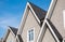 Top of the house with dormer in the blue sky. Houses with shingle roof. Edge of roof shingles on top of the house