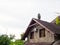 Top of the house with two windows, granite cladding and a tiled roof with antennas against a cloudy sky