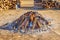 Top of a large circular bonfire packed with firewood on the sides that smoke comes from the wooden logs in a popular village