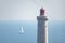 Top of a lighthouse on the sea with a sailboat