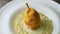 Top macro view breaded whole pear on boiled barley porridge rotates on white plate