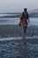 Top model in poncho walking on sandy strange beach