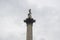 Top of Nelson`s column in Trafalgar Square, London against a grey overcast sky.