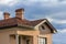 Top of new big modern house with shingled red roof, two high chimneys, snow protection low fence and plastic windows against brigh