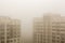 Top part of highrise modern apartment building facade during heavy fog weather