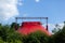 Top of red circus tent peaking behind the trees, blue sky