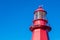 Top of a red lighthouse over blue sky