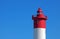 TOP OF RED AND WHITE LIGHTHOUSE AGAINST BLUE SKY