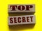 Top Secret words on wooden building blocks isolated on yellow. Marketing or yellow press scandal reveal concept