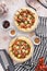 Top vertical shot of a kitchen table with delicious pizza, brown olives, tomatoes, and spices