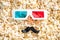 top view of 3d glasses and artificial mustache on scattered popcorn, cinema concept.